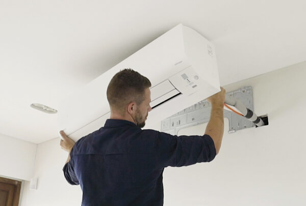 the-ac-technician-fitting-the-ac-on-the-wall